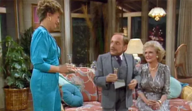 Rose and her partner Jonathan sitting on the couch talking to Blanche who is standing. 